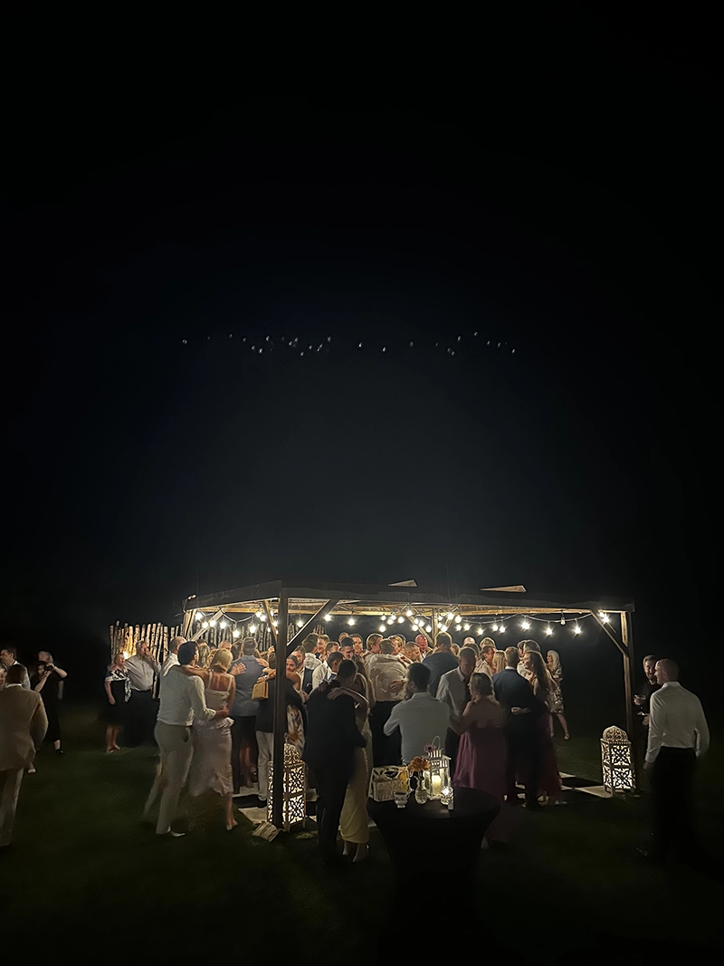 Guests dancing beneath string lights at a private cottage wedding